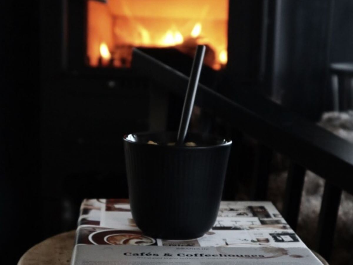 En kopp med varm kakao står foran en peis