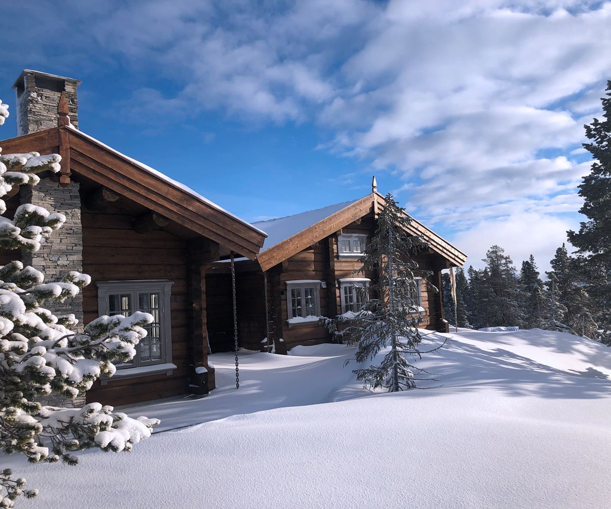 En hytte i brunt tre ligger i snødekte omgivelser